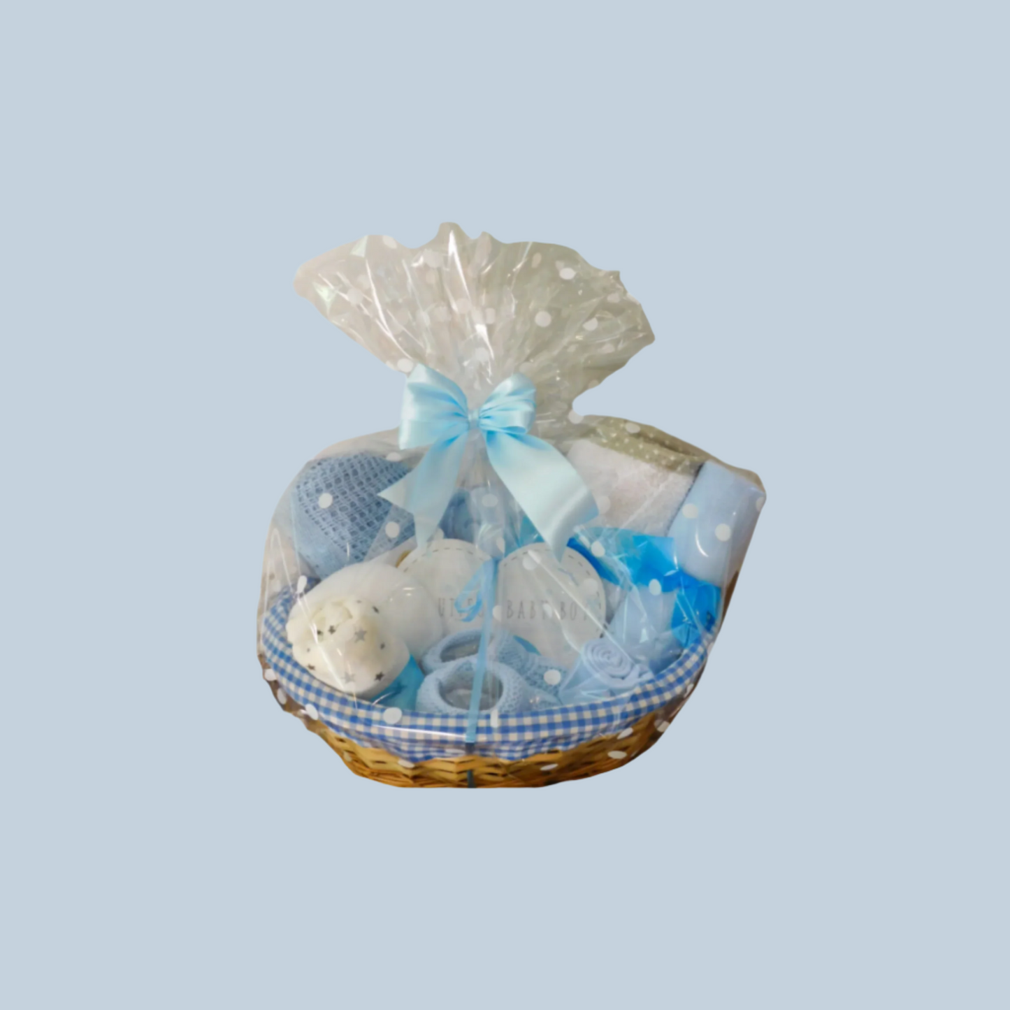 Baby gift basket with toys and items wrapped in cellophane on a pale blue background