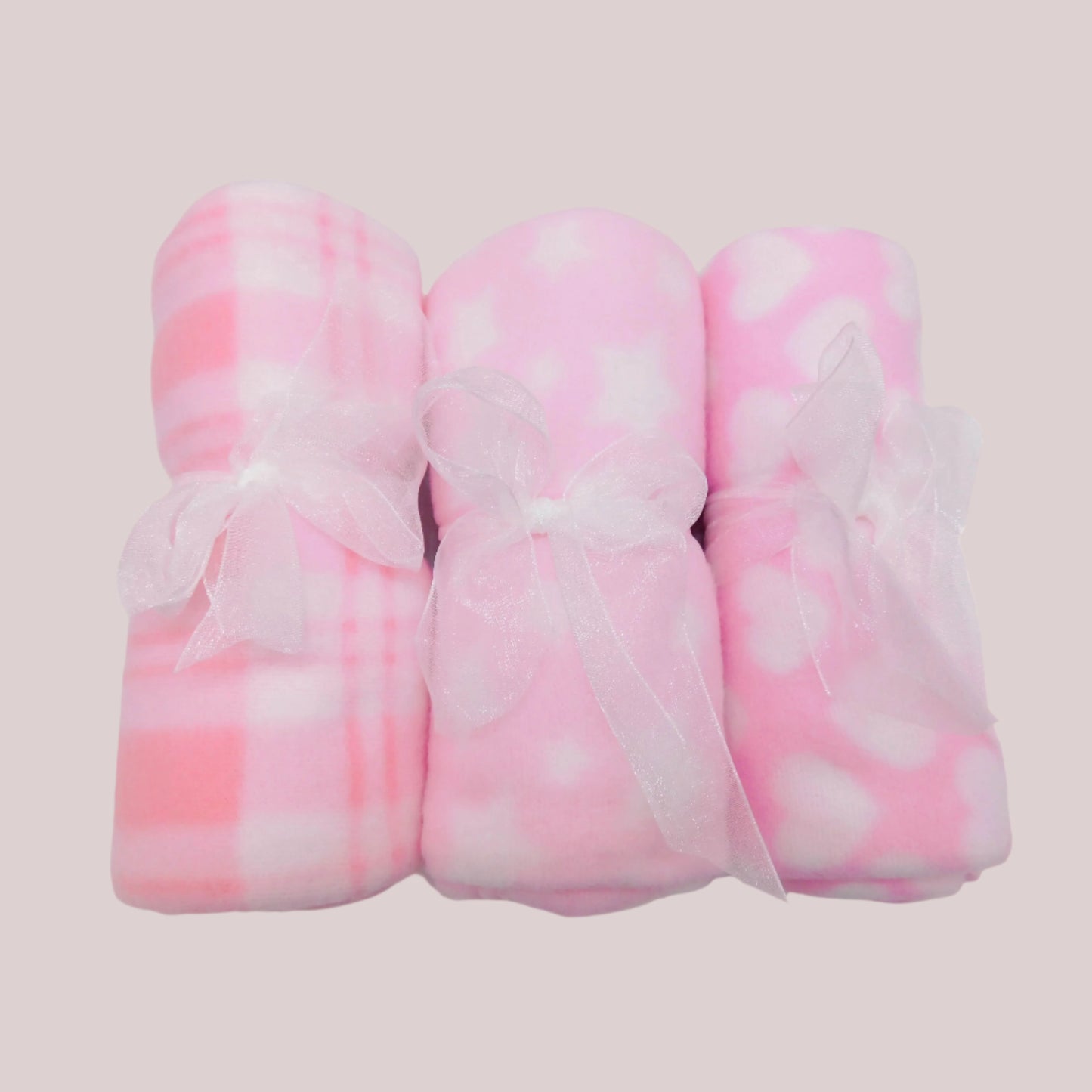 Three pink and white patterned fleece blankets on a pale pink background