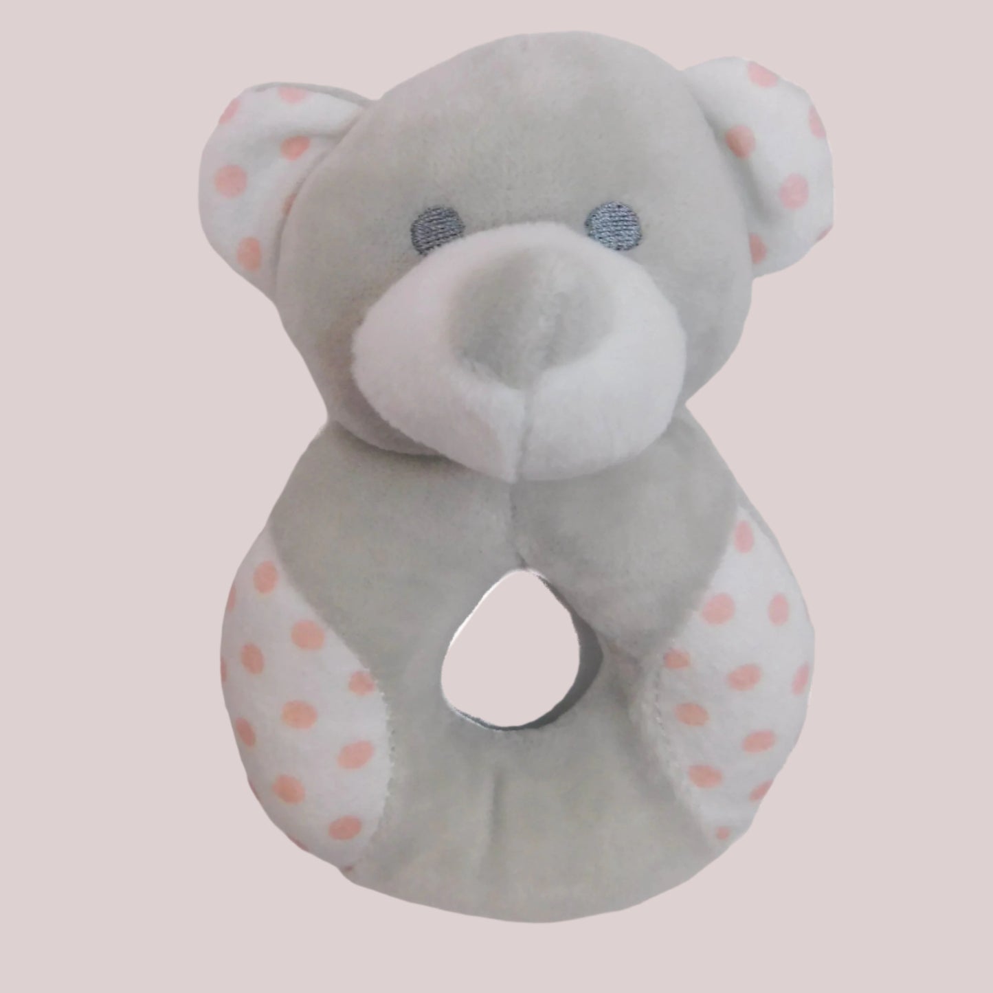 Gray teddy bear-shaped plush rattle with pink polka dots on a pale pink background