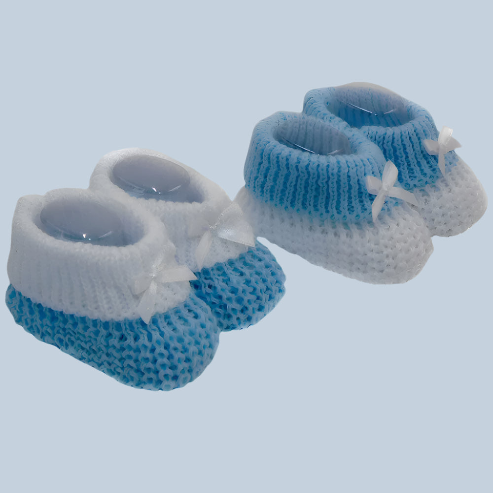 Pair of blue and white knitted baby booties on a pale blue background