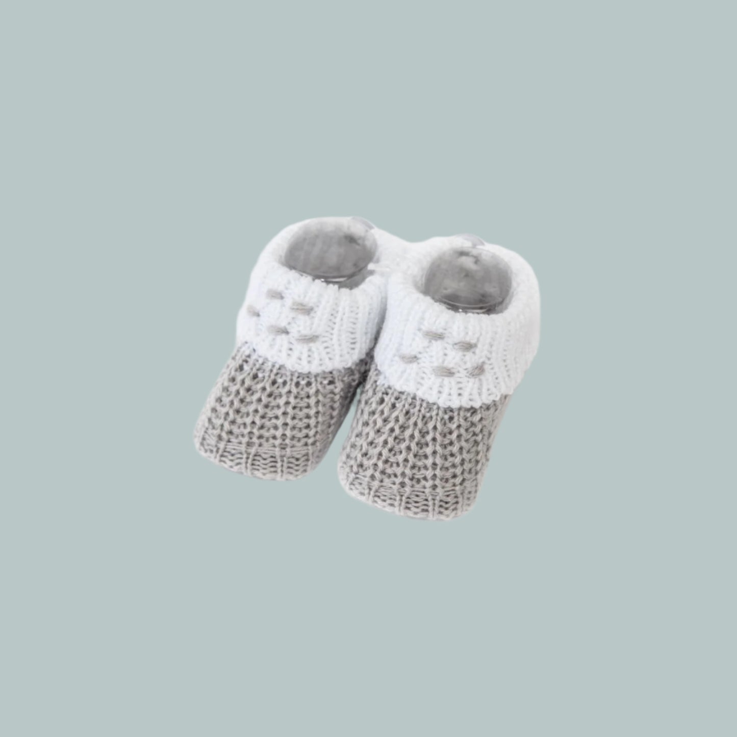 Pair of gray and white baby booties on a neutral background