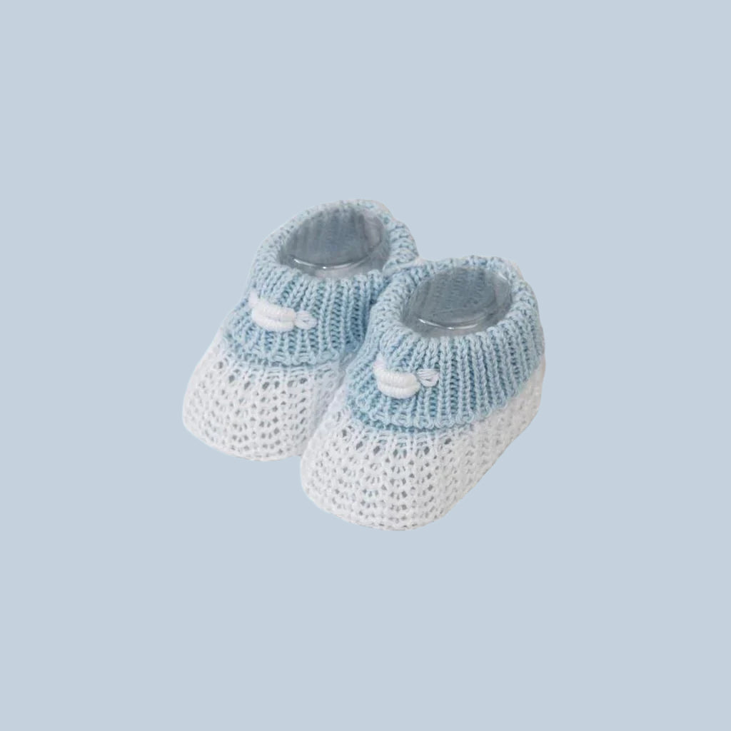 Pair of blue and white knitted baby booties on a blue background