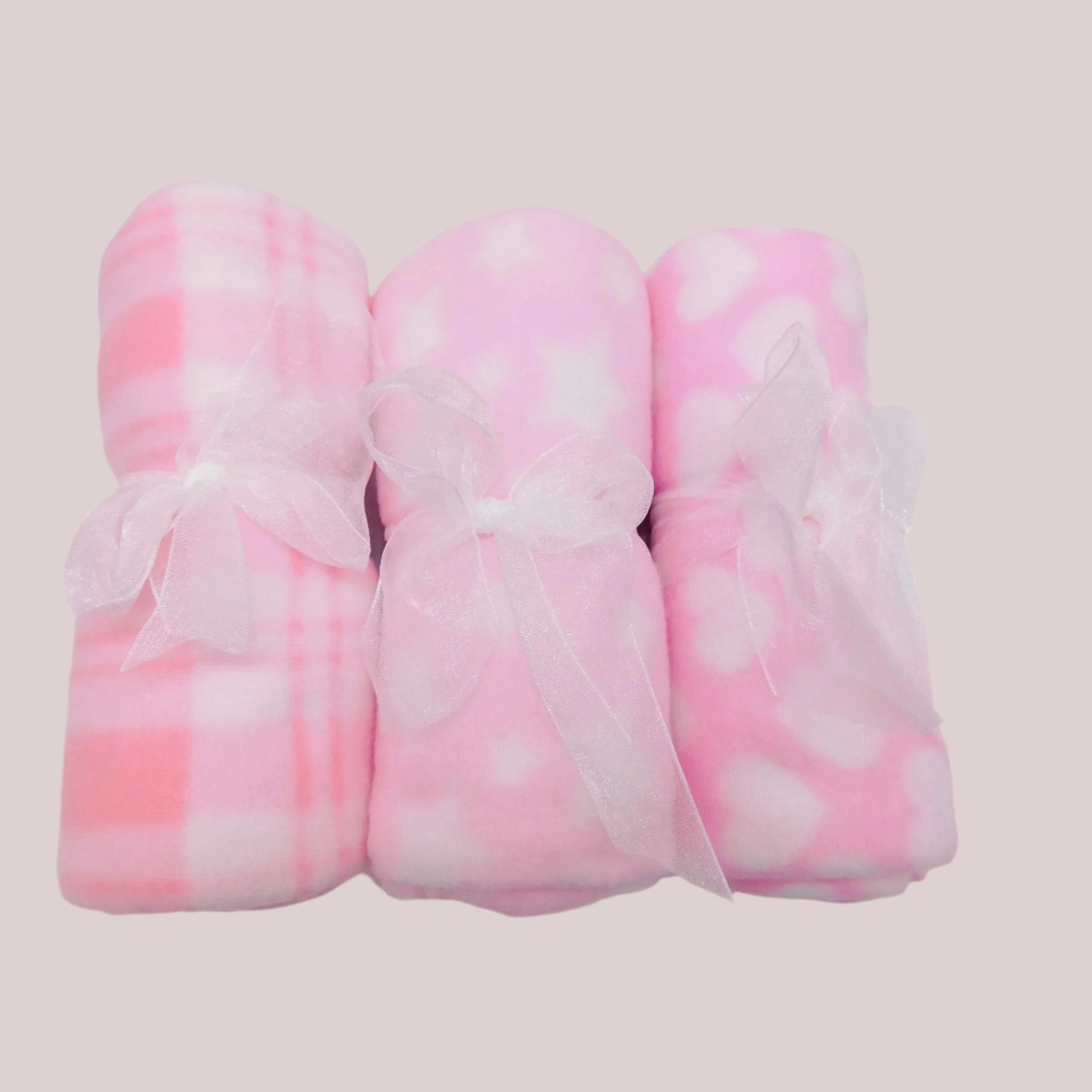 Three pink and white patterned fleece blankets on a pale pink background