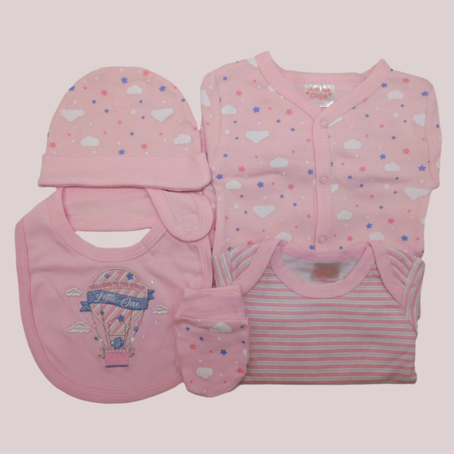 Baby clothing set with pink sleepsuit, bodysuit, bib, hat, and mittens on a pale pink background