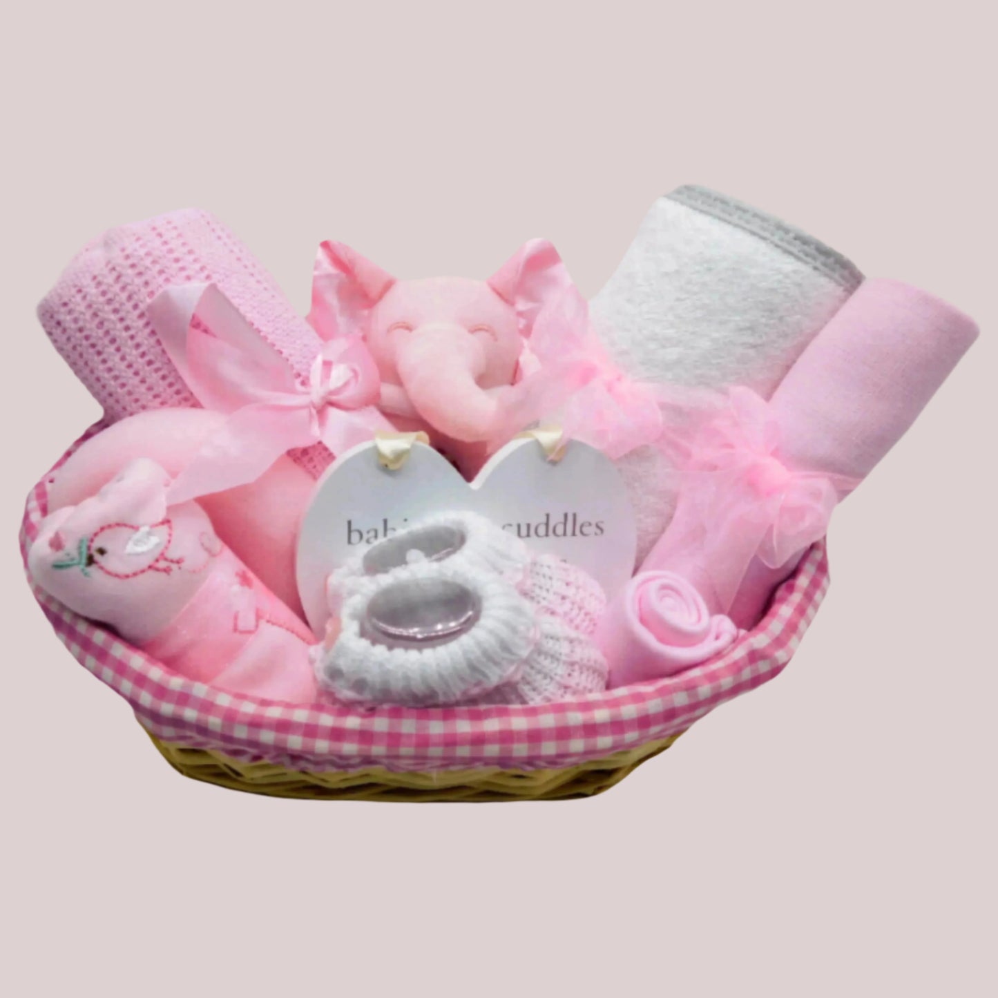 Baby gift basket with pink and white items on a pink background