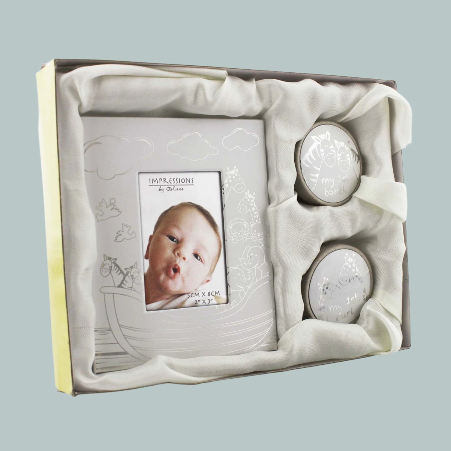 Baby photo frame and two round keepsakes for my first tooth and curl in a decorative box with a neutral background.