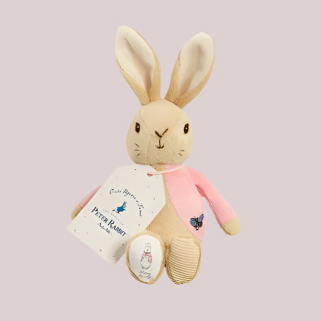 Plush Flopsy Bunny bean rattle with a pink outfit and a tag on a pale pink background