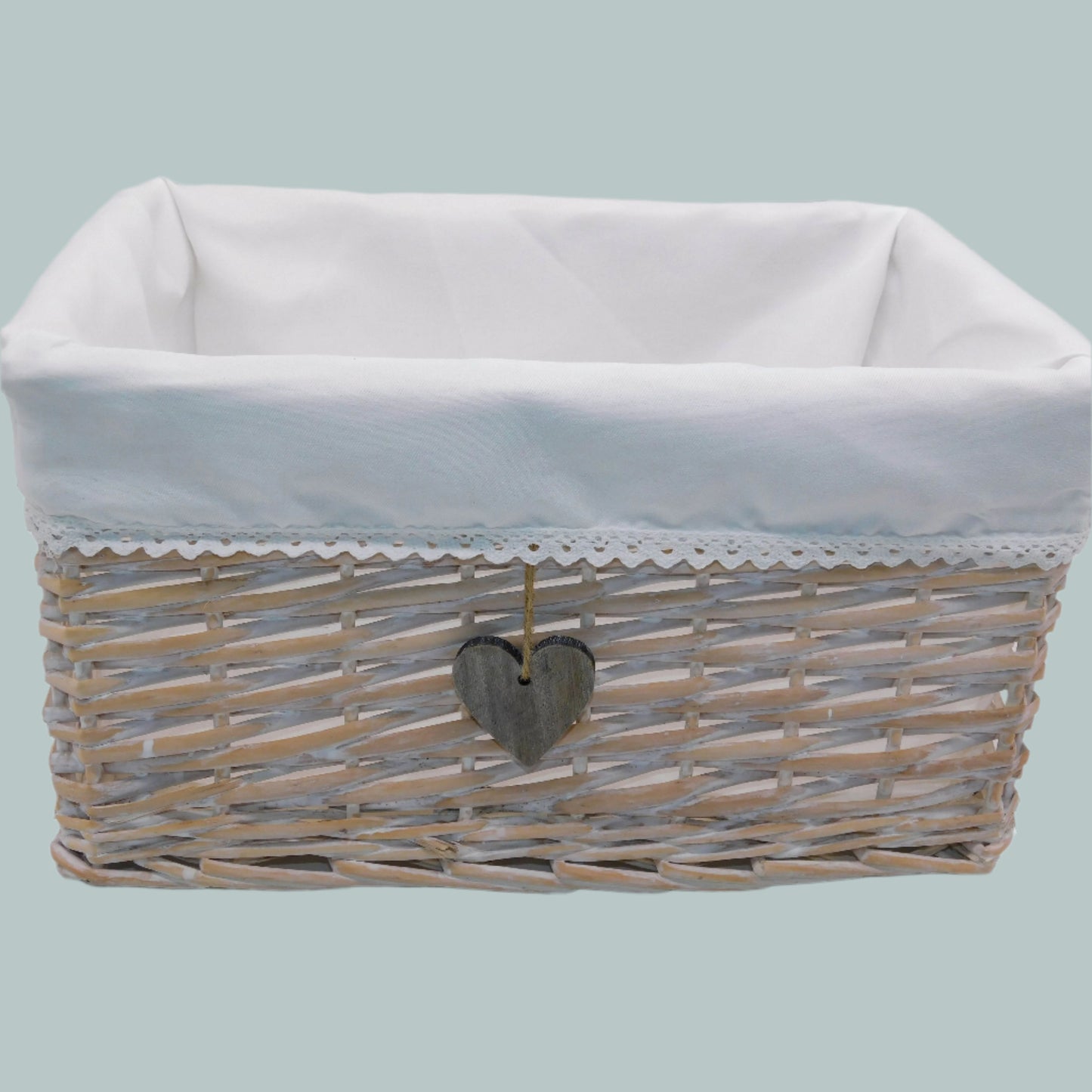 Wicker basket with white liner and heart-shaped tag on a neutral background