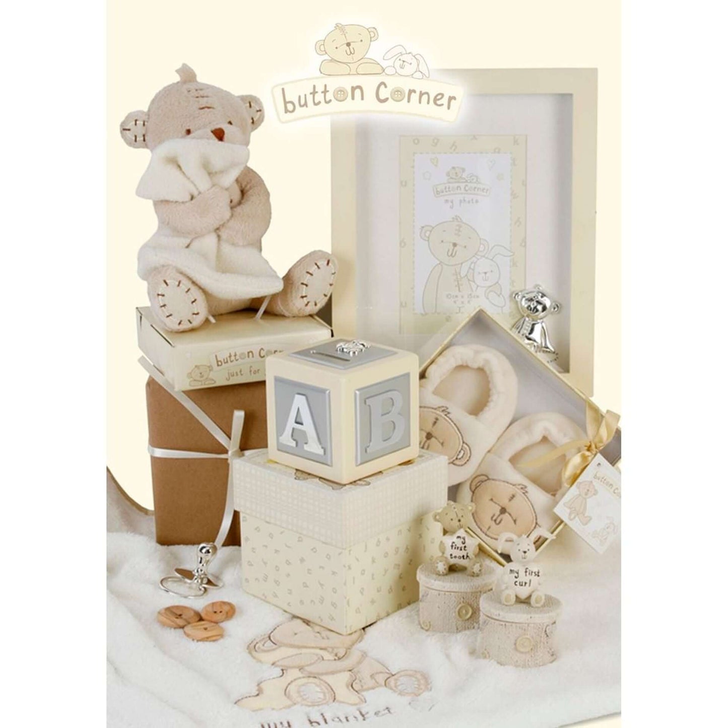 Collection of baby-themed decorative items including a teddy bear, blocks, photo frame and Button Corner tooth and curl boxes on a white background.