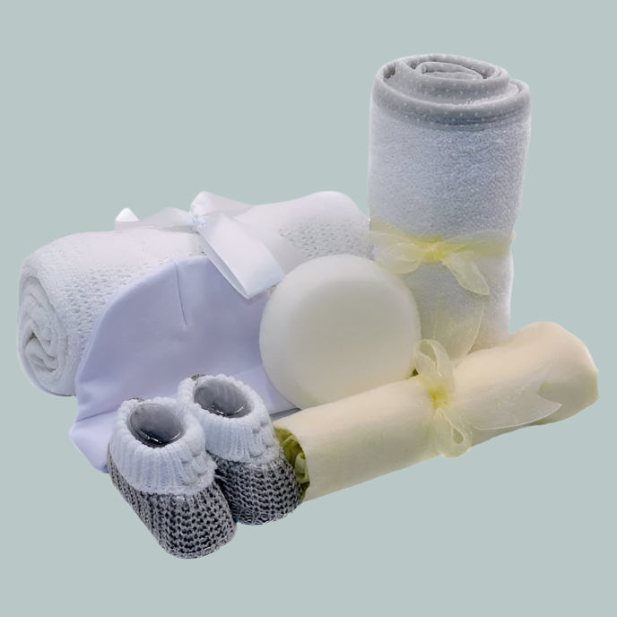 Baby gift set with blanket, booties, muslin square, hooded towel, hat and a sponge on a neutral background