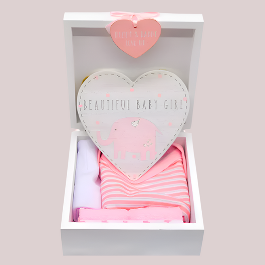 Baby girl gift set with heart-shaped elephant hanging door plaque, pink and white bodysuit, white hat, and washcloths in a keepsake box with a heart-shaped tag.