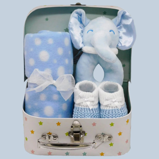Baby gift set with blue elephant toy, blanket, and booties in a suitcase-shaped box.
