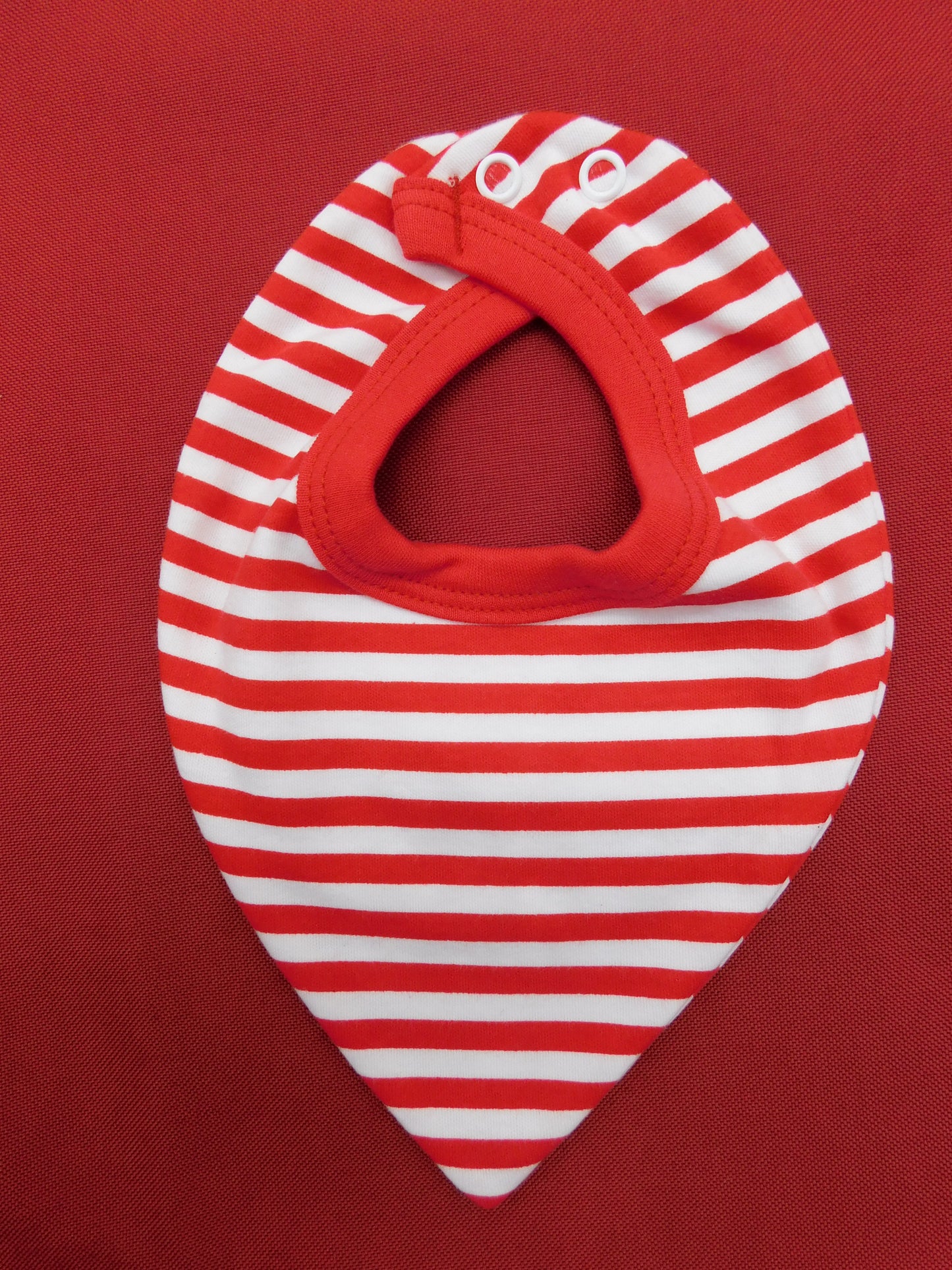 Red and white striped baby bib on a red background