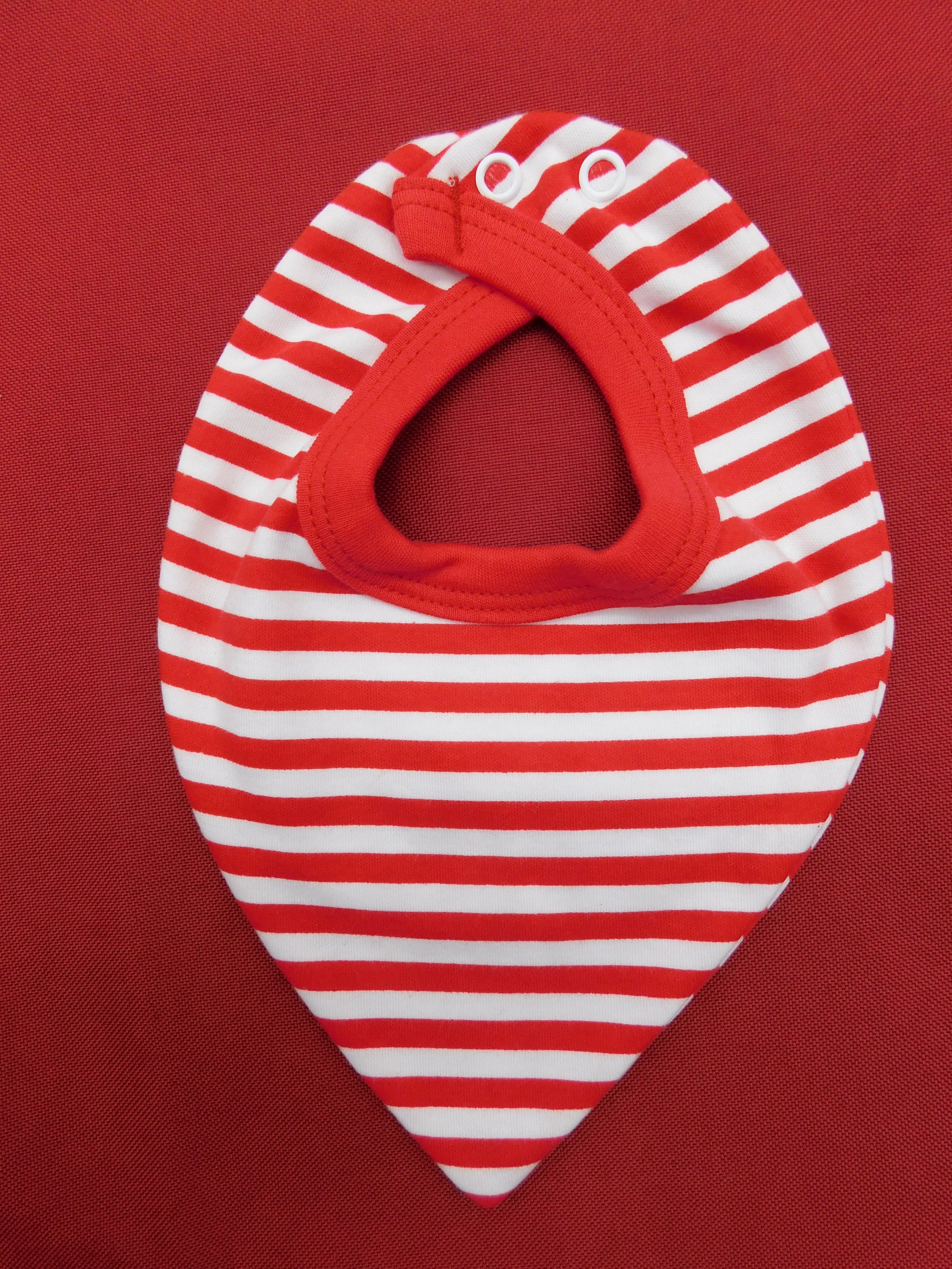 Red and white striped baby bib on a red background