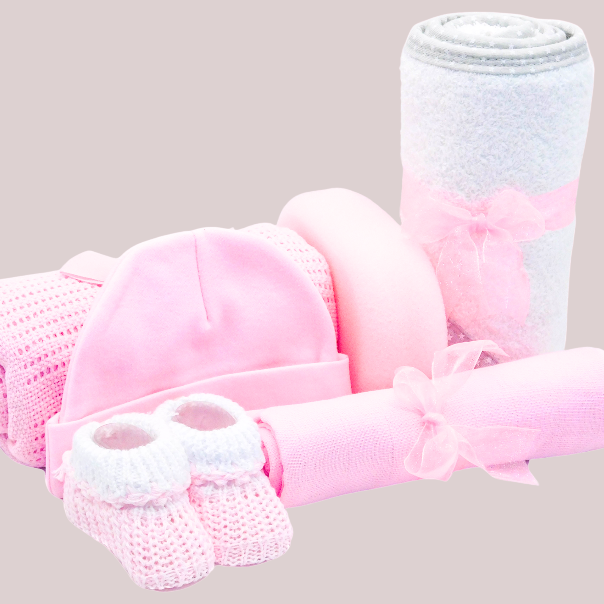 Flat lay baby essentials in pink & white, including towel, hat, blanket, sponge, muslin & booties