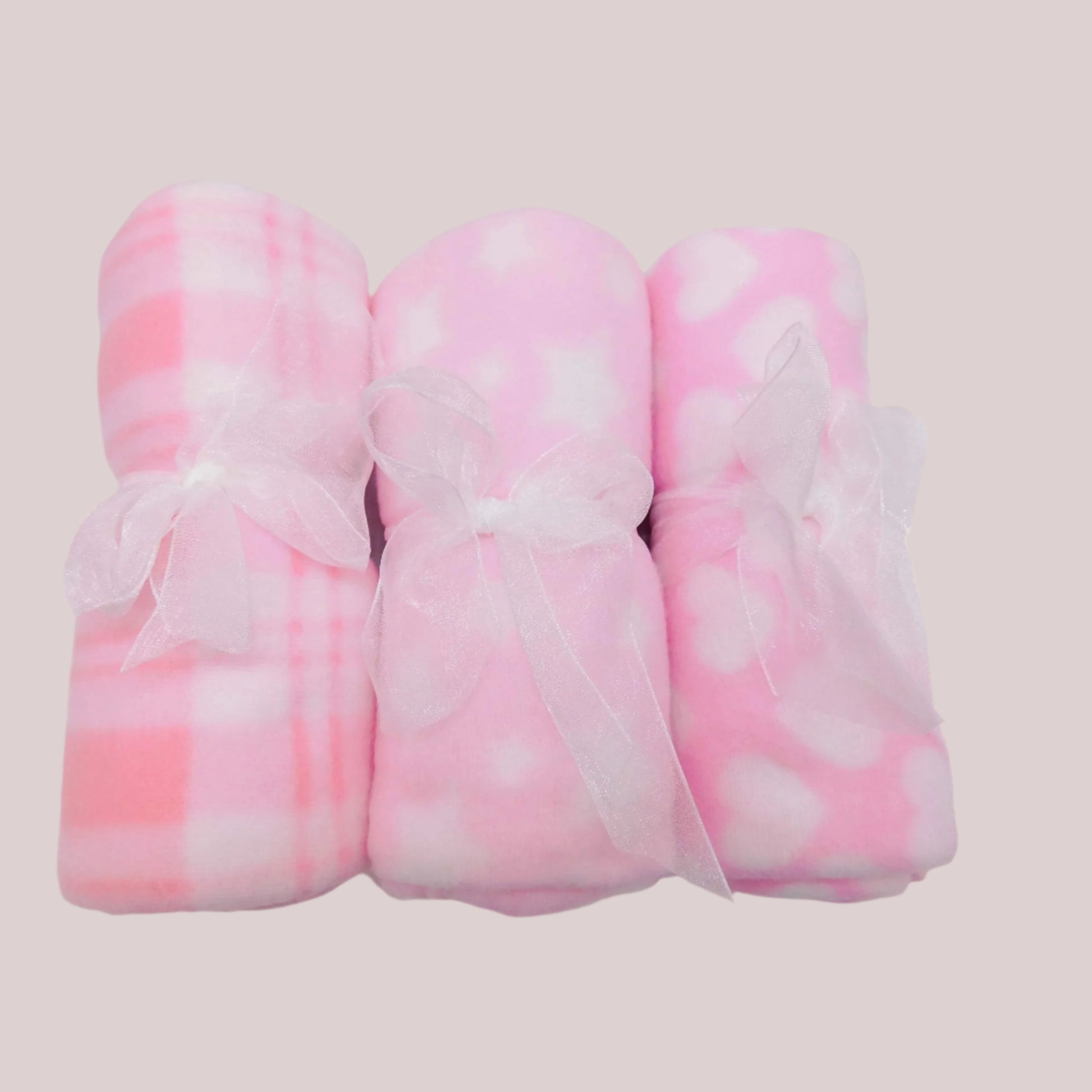 Three pink and white patterned fleece blankets on a pale pink background