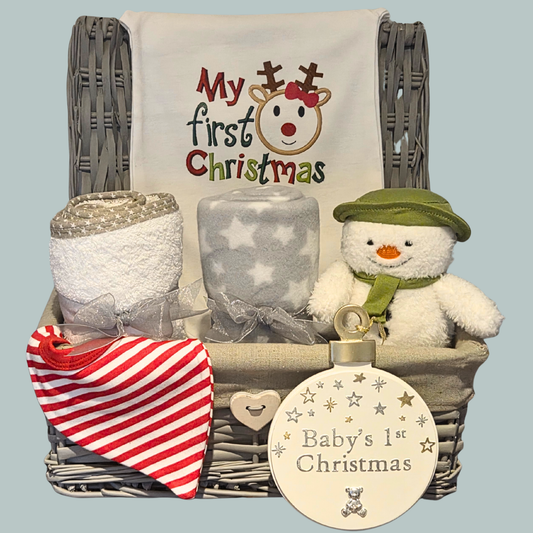 Wicker gift basket displaying 'my first christmas' romper, towel, blanket, Snowman toy, striped bib and 'Baby's 1st Christmas' plaque