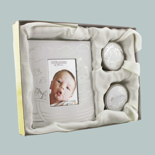 Baby photo frame and two round keepsakes for my first tooth and curl in a decorative box with a neutral background.