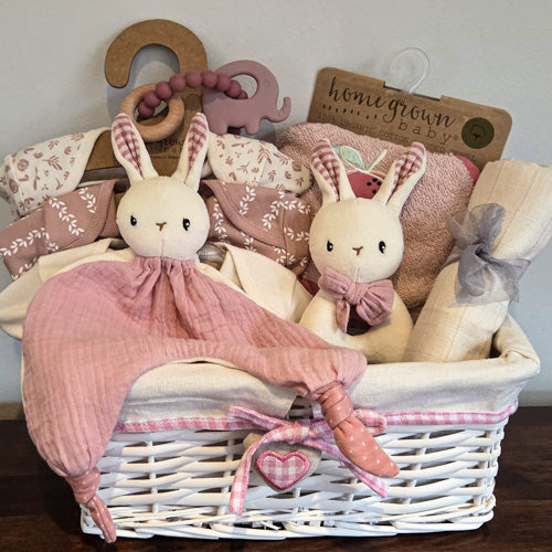 Baby gift basket, white wicker  with gingham trim & plush heart, pink and cream bodysuits, muslin, pink & white bunny comforter and rattle, towel and elephant teething beads