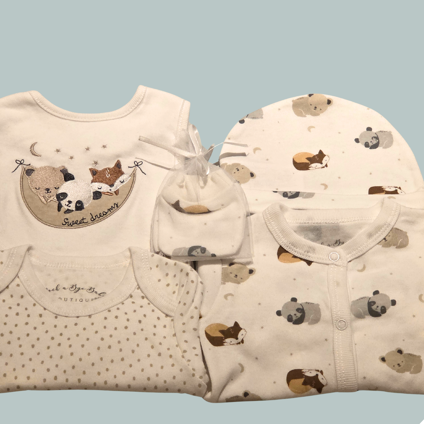 Baby bodysuit, sleepsuit, bib, hat and mittens with a sleepy animal theme on a light teal background