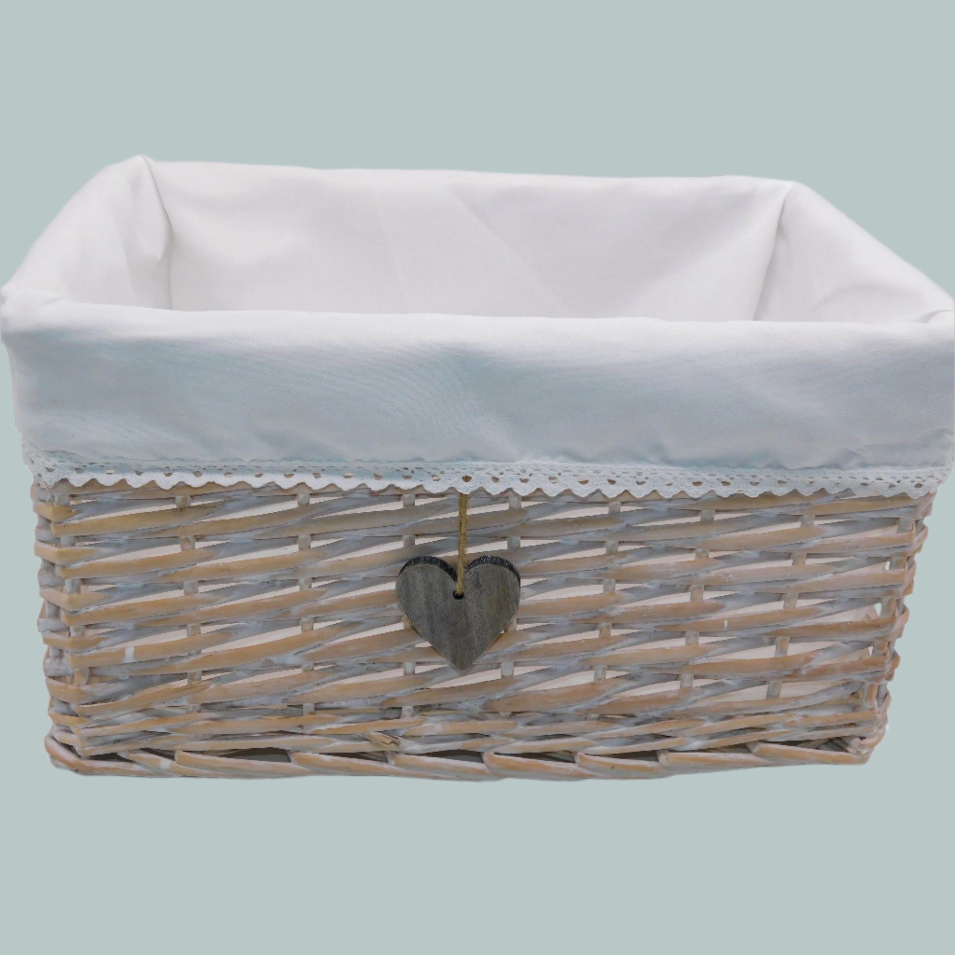 Wicker basket with white liner and heart-shaped tag on a neutral background
