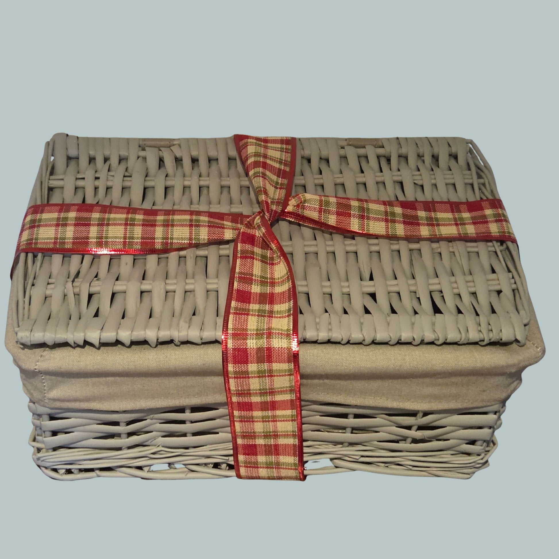 Grey wicker hamper basket wrapped with a tartan  ribbon 