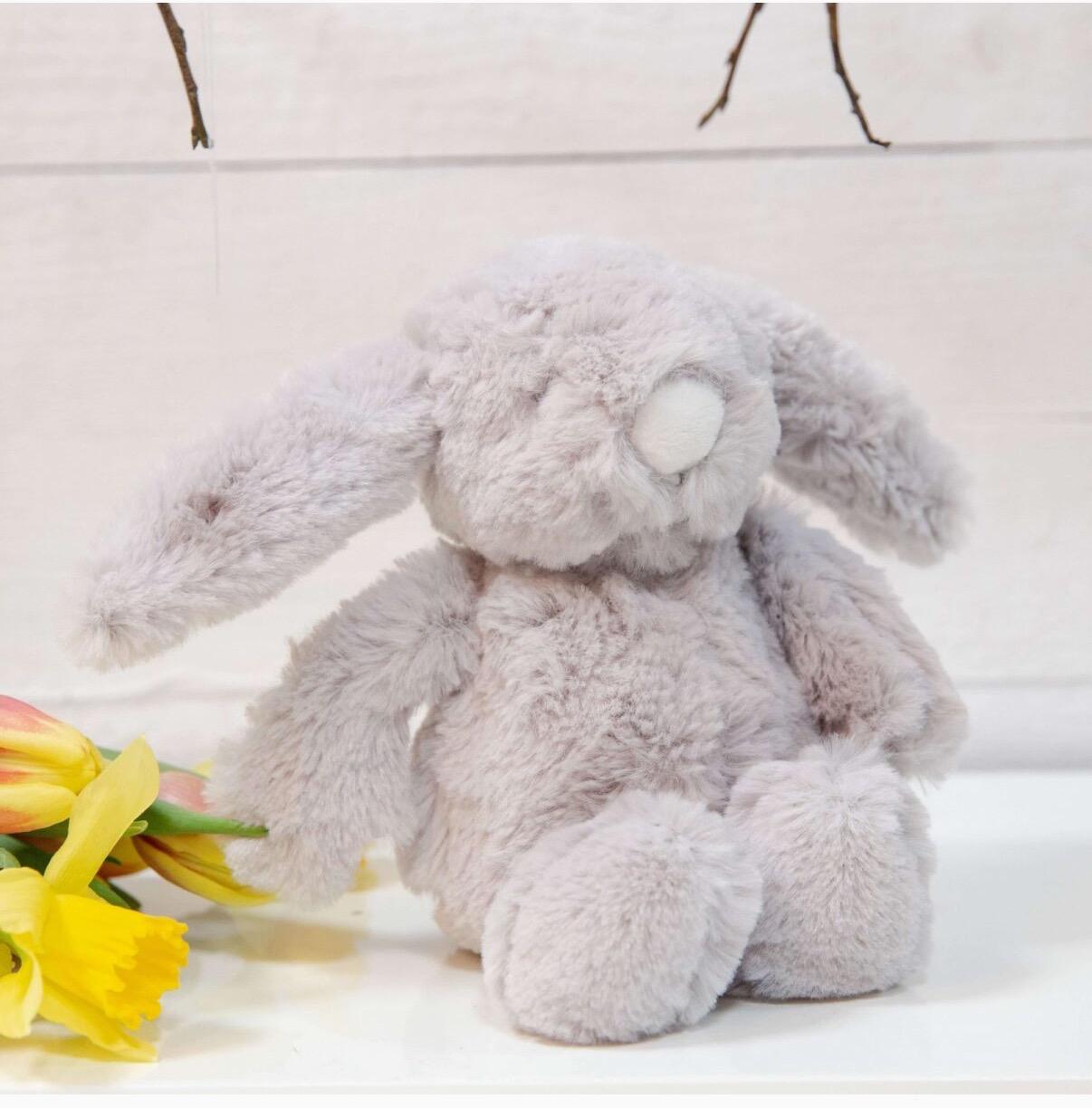 Plush grey bunny toy with yellow flowers on a light background
